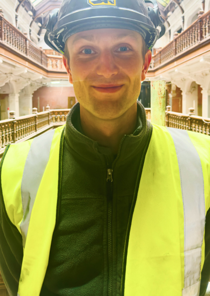 Project Engineer wearing a black branded hard hat and yellow Hi-Vis vest