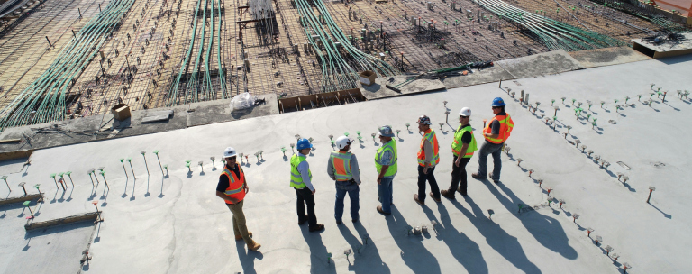 A team of people on a construction site wearing protective PPE including hard hats and hi-vis vests